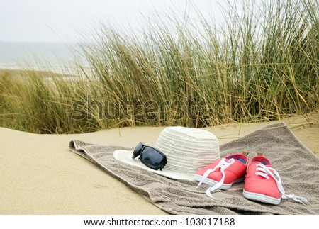 sun hat, shoes and sun glasses on beach towel in sand dunes