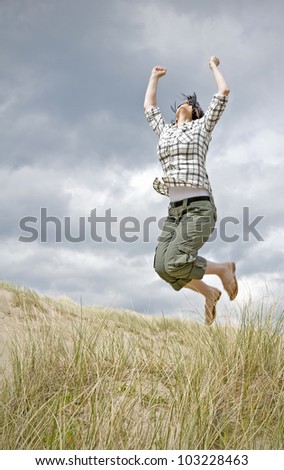 woman jumping for joy in sand dunes