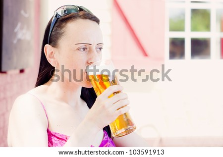 woman drinking a pint of lager in a pub beer garden landscape