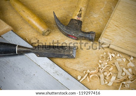 carpentry tools including chisel, hammer, saw and wood on workbench