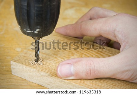 person drilling into wood using electric drill