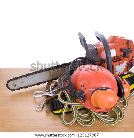 tree surgeon tools including chainsaw, helmet, harness, ear defenders and rope on desk