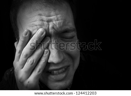 man feeling upset, crying with hand on head with black background