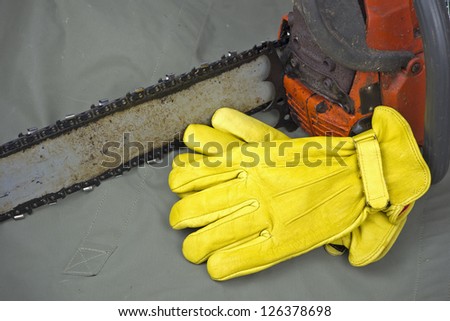 yellow leather work gloves with chainsaw and copyspace