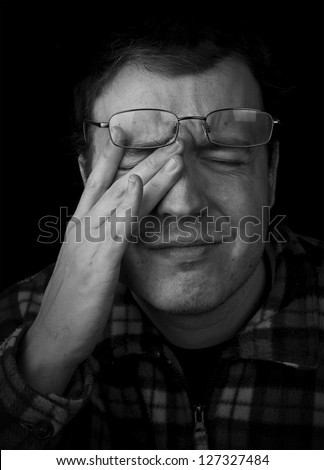 man wearing glasses with eye strain, frowning with hand on head black and white