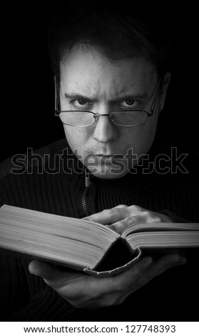 man with book looking at camera, studying black and white portrait