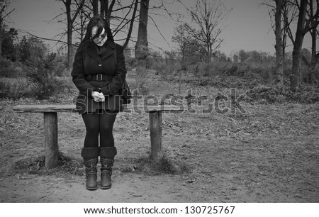 woman alone on park bench looking sad, black and white landscape
