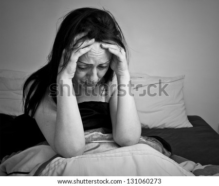 woman upset, crying lying in bed in bedroom black and white with copy space