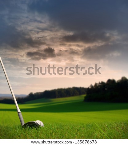 chipping a golf ball onto the green / fairway with golf club at sunset with copy space