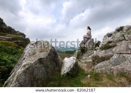 a woman sitting on a rock high up on a mountain