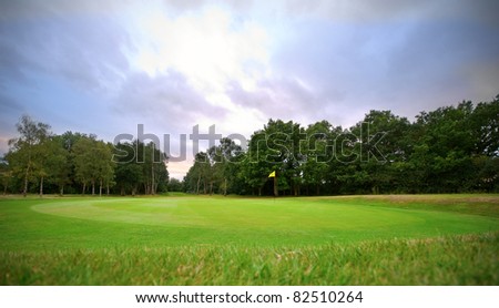 golf putting green with flag at sunset
