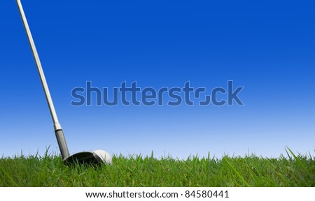 hitting golf ball with club on grass with blue sky background