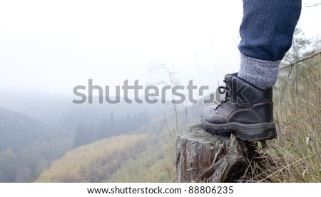 person walking above misty valley showing walking boot only