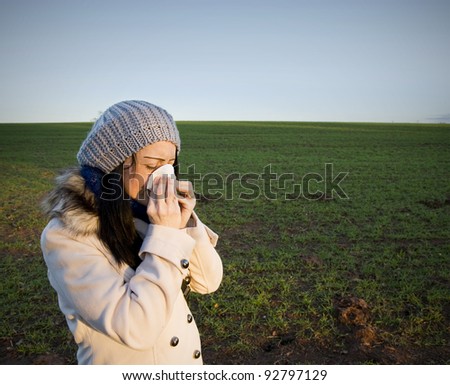 A Woman in countryside blowing her nose
