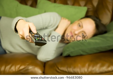 woman lying on sofa pointing remote control