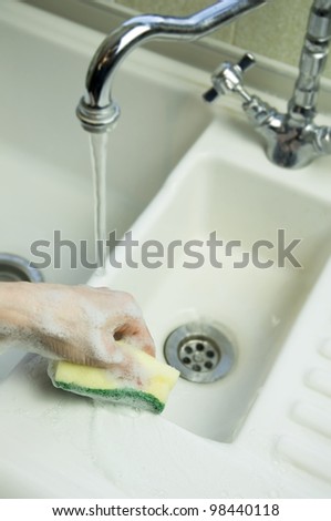 woman cleaning sink with sponge scouring pad