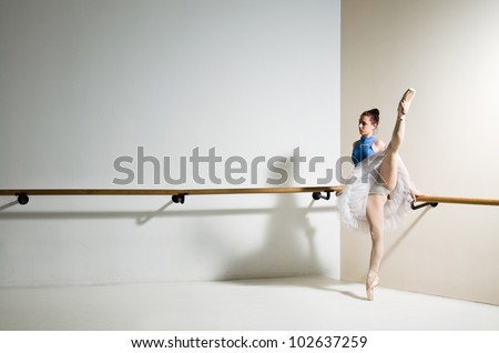 beautiful classic ballet dancer in white tutu posing on one leg
