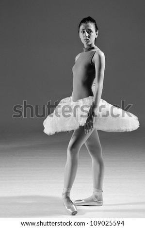 Beautiful ballerina standing in white tutu and ballet slipper, gray scale image.