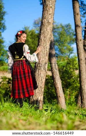 Young woman dressed in traditional Serbian clothing posing in the woods