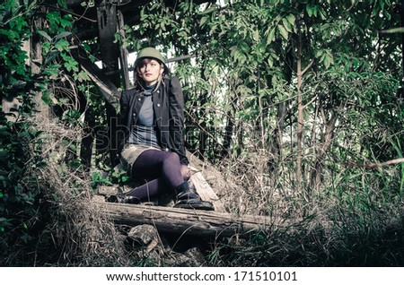 Attractive young female posing in army clothes at devastated place