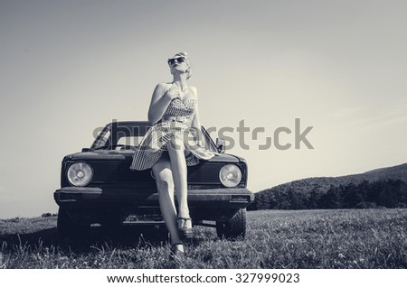 Young attractive female model in short skirt posing and teasing next to retro car. Vintage style.