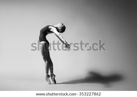 Ballerina in black outfit posing on toes, studio background. Grayscale image.