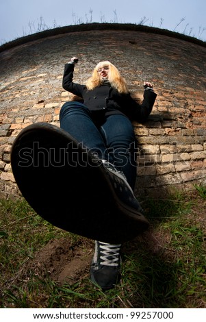 Funny blond girl posing against brick wall. Dynamic composition.