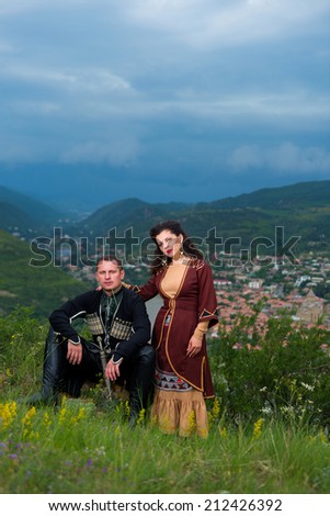 Man and woman in Georgian national dress on a background of mountains
