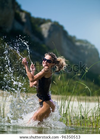 Girl Splashing in the sea water on a background of mountains