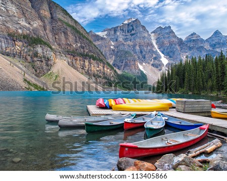 Beautiful Scene In One Of The Rocky Mountain Lakes - Moraine Lake, Banff National Park - Canada. View Of Canoes On The Dock By The Lodge.