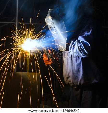 welder with protective mask welding metal and sparks