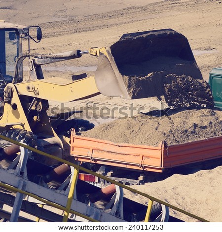 wheel loader excavator machine loading dumper truck at sand quarry