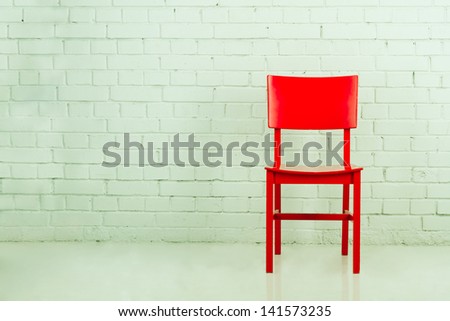 Red chair in empty room against a brick wall with copy-space