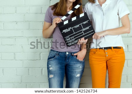 Two young girls holding a clapboard against brick wall with copy-space