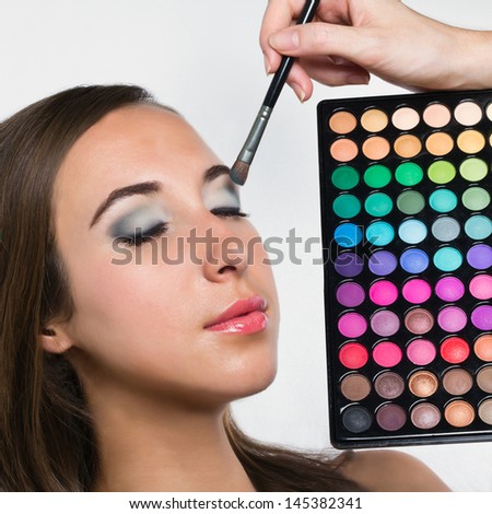 Young woman at beauty salon. Applying eye shadows. Eye shadow brush. Make-up.