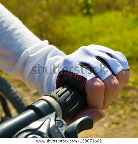 Hand holding a handle bar. Woman riding a bicycle in a park