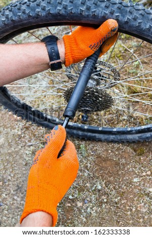 Bike maintenance pumping up tyre. Closeup of mechanic pumping a bicycle tire