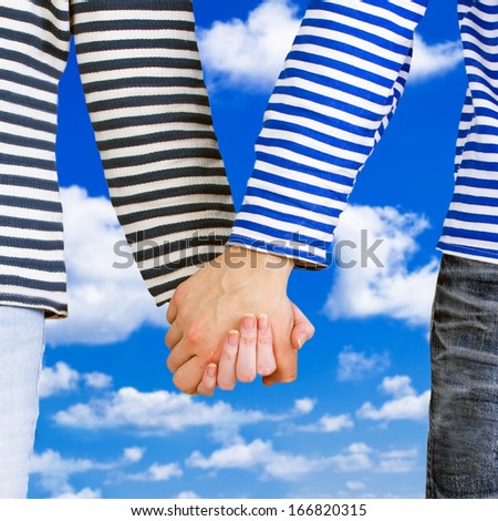 Man and woman holding hands together over blue sky background. Young couple wearing marine sailor uniform holding hands illustrating love and friendship