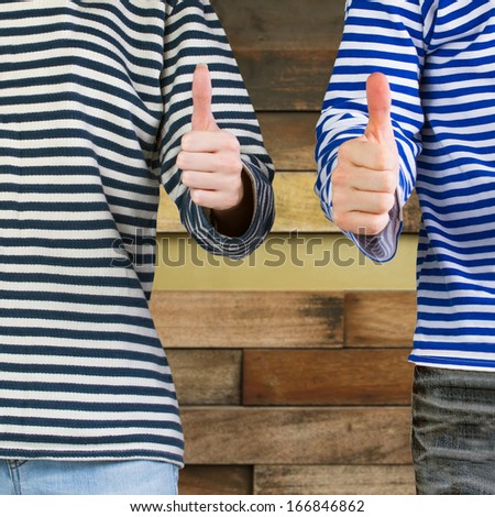 Man and woman with thumbs up sign over wooden background with copy space. Young couple showing thumbs up sign