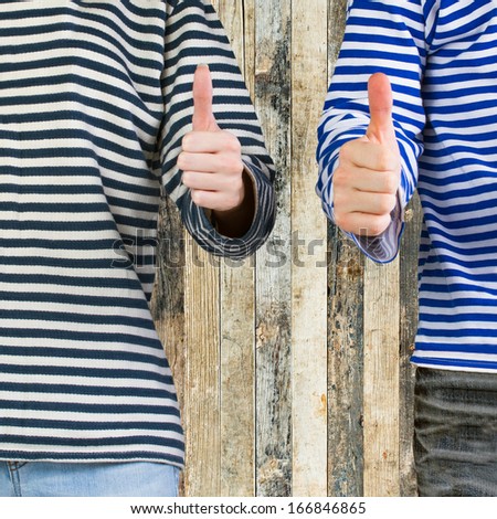 Man and woman with thumbs up sign over wooden background with copy space. Young couple showing thumbs up sign