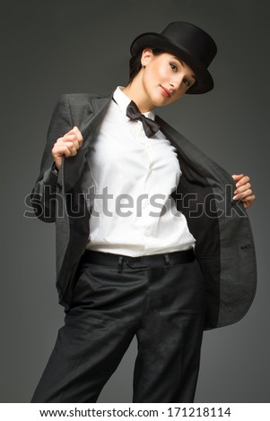 Young woman wearing man\'s suit posing over grey background. Woman feels like a man - concept. Retro style young woman against grey background.
