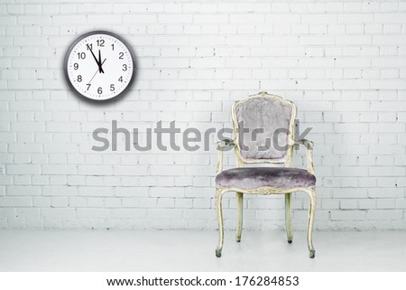 Vintage chair against white brick wall with clock