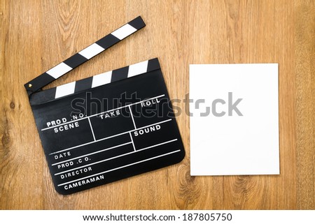 Movie production clapper board with empty paper against wooden background