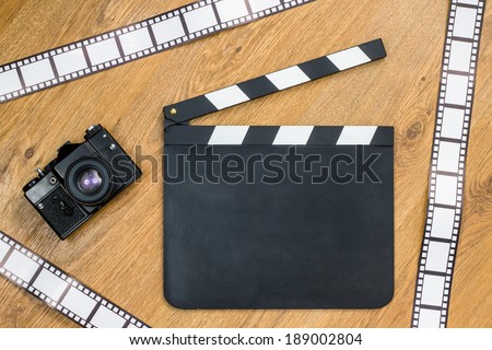 Blank film slate, vintage camera and film strips with copy space against wooden background