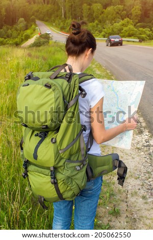 Young woman hiker reading map on hiking trip. Female trekker