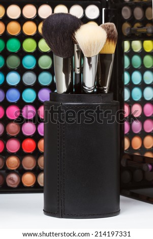 Makeup brushes against colorful makeup palette