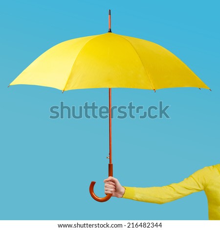 Hand holding an umbrella against a blue backgroud