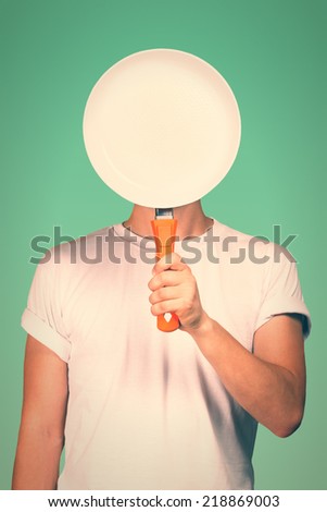 Man covering face with a blank pan. Toned image