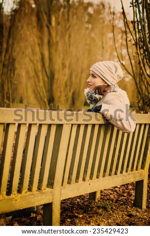 Woman sitting on bench in autumn park. Toned image