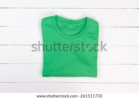 Green folded t-shirt on white wooden background